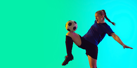 Image showing Female soccer, football player kicking ball, training in action and motion with bright emotions isolated on gradient background. Flyer with copyspace.