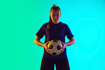 Image showing Female soccer, football player holding ball, posing confident isolated on gradient background. Copyspace.