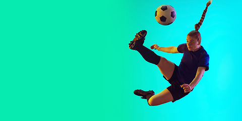 Image showing Female soccer, football player kicking ball, training in action and motion with bright emotions isolated on gradient background. Flyer with copyspace.