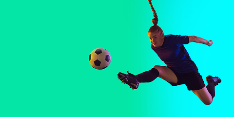 Image showing Female soccer, football player kicking ball, training in action and motion with bright emotions isolated on gradient background. Flyer with copyspace.