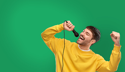 Image showing man in yellow sweatshirt with microphone singing