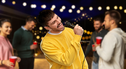 Image showing man with microphone singing at night rooftop party