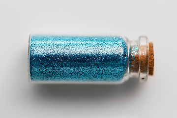 Image showing blue glitters in bottle over white background