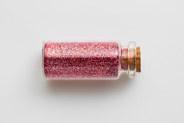 Image showing red glitters in bottle over white background