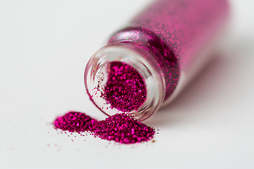 Image showing pink glitters poured from small glass bottle