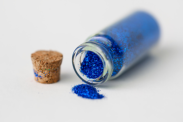 Image showing blue glitters poured from small glass bottle