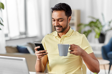 Image showing man with smartphone drinking coffee at home office