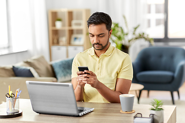 Image showing happy indian man with smartphone at home office