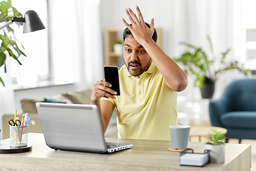 Image showing angry indian man with smartphone at home office