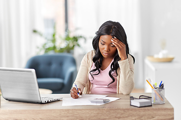 Image showing woman with calculator and papers working at home