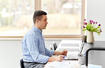 Image showing man in earphones with laptop working at home