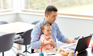 Image showing father with baby working on laptop at home office