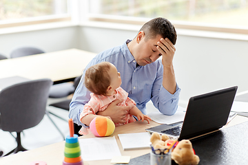 Image showing father with baby working on laptop at home office