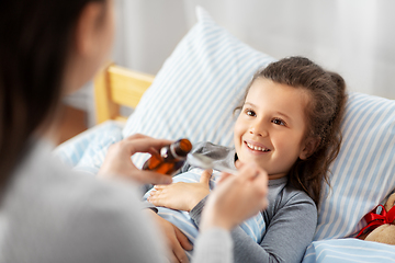 Image showing mother pouring cough syrup for sick daughter