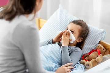 Image showing mother and ill little daughter blowing nose in bed