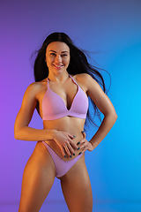 Image showing Fashion portrait of young fit and sportive woman in stylish purple luxury swimwear on gradient background. Perfect body ready for summertime.
