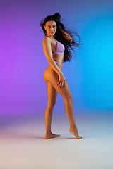 Image showing Fashion portrait of young fit and sportive woman in stylish purple luxury swimwear on gradient background. Perfect body ready for summertime.