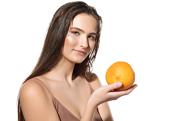 Image showing Close up of beautiful female face with orange over white background. Cosmetics and makeup, natural and eco treatment, skin care.