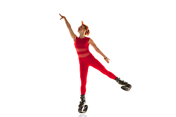 Image showing Beautiful redhead woman in a red sportswear jumping in a kangoo jumps shoes isolated on white studio background.