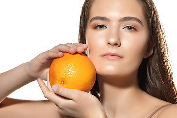 Image showing Close up of beautiful female face with orange over white background. Cosmetics and makeup, natural and eco treatment, skin care.