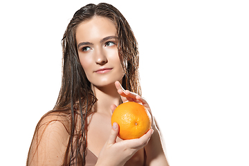 Image showing Close up of beautiful female face with orange over white background. Cosmetics and makeup, natural and eco treatment, skin care.