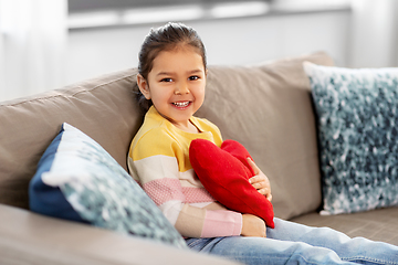 Image showing happy little girl with heart shaped pillow at home