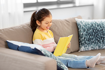 Image showing happy smiling little girl reading book at home