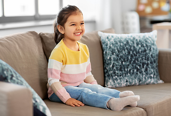 Image showing happy smiling little girl sitting on sofa at home