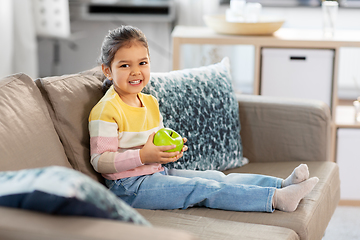 Image showing happy little girl with apple sitting on sofa