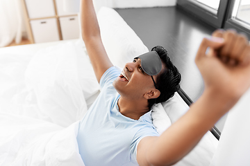 Image showing happy smiling indian man lying in bed at home