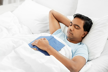 Image showing indian man with book sleeping in bed at home