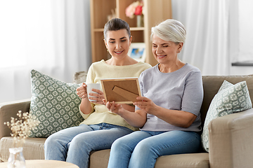 Image showing adult daughter and old mother with photo at home