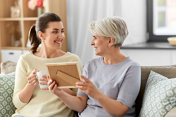 Image showing adult daughter and old mother with photo at home