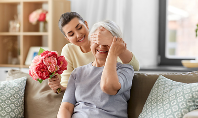 Image showing adult daughter giving flowers to old mother