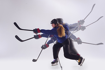 Image showing Young female hockey player with the stick on ice court and white background, action and motion concept