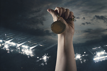 Image showing Award of victory, male hands tightening the medal of winners against cloudy dark sky