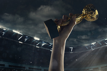 Image showing Award of victory, male hands tightening the cup of winners against cloudy dark sky