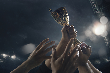 Image showing Award of victory, male hands tightening the cup of winners against cloudy dark sky