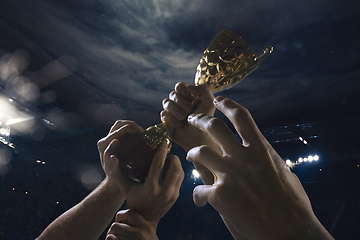 Image showing Award of victory, male hands tightening the cup of winners against cloudy dark sky