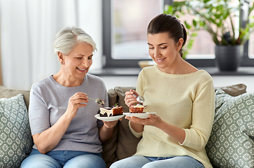 Image showing old mother and adult daughter eating cake at home