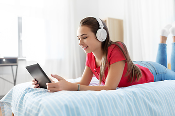 Image showing girl in headphones listening to music on tablet pc