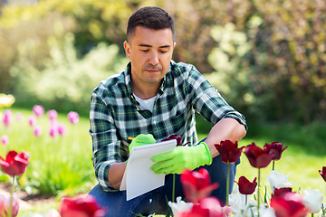 Image showing man with notebook and flowers at summer garden