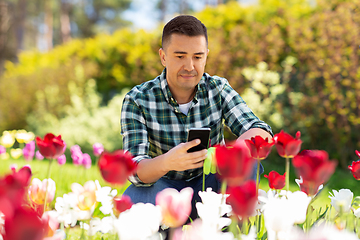 Image showing middle-aged man with smartphone at flower garden