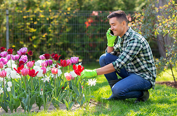Image showing man with flowers calling on smartphone at garden