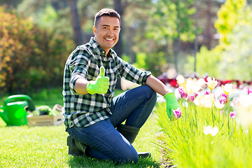 Image showing happy man with flowers showing thumbs up at garden