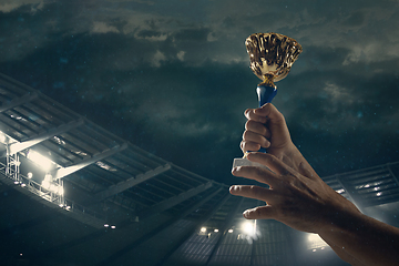 Image showing Award of victory, male hands tightening the cup of winners against cloudy dark sky