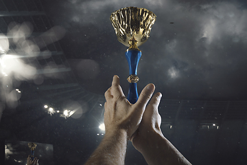 Image showing Award of victory, male hands tightening the cup of winners against cloudy dark sky