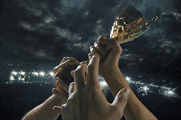 Image showing Award of victory, male hands tightening the cup of winners against cloudy dark sky