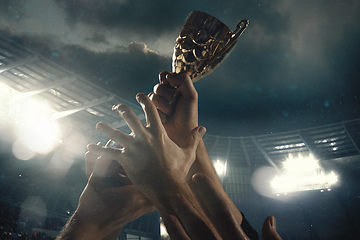 Image showing Award of victory, male hands tightening the cup of winners against cloudy dark sky