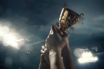 Image showing Award of victory, male hands tightening the cup of winners against cloudy dark sky